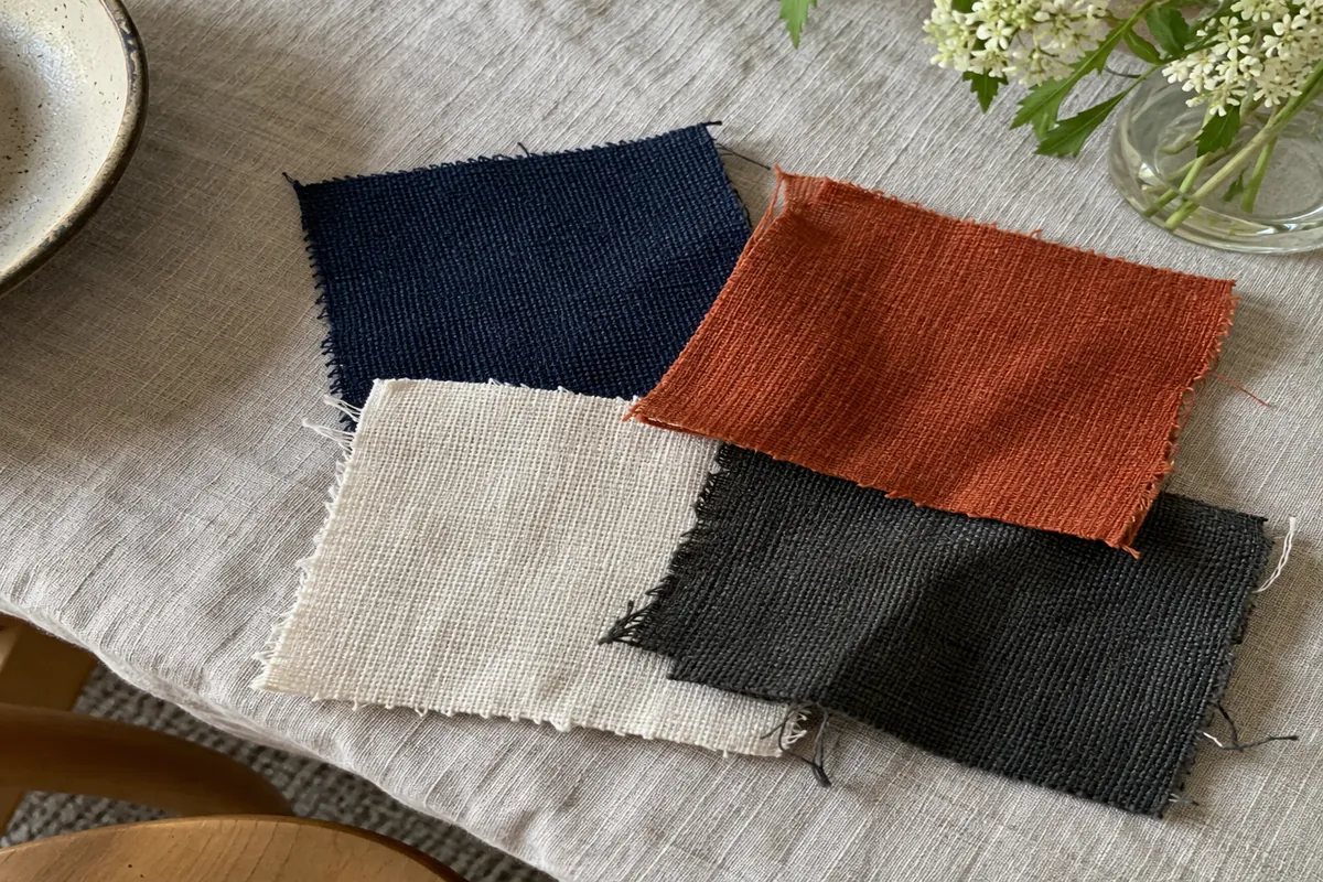 A small palette of fabric swatches in navy, rust, cream and charcoal on a linen tablecloth